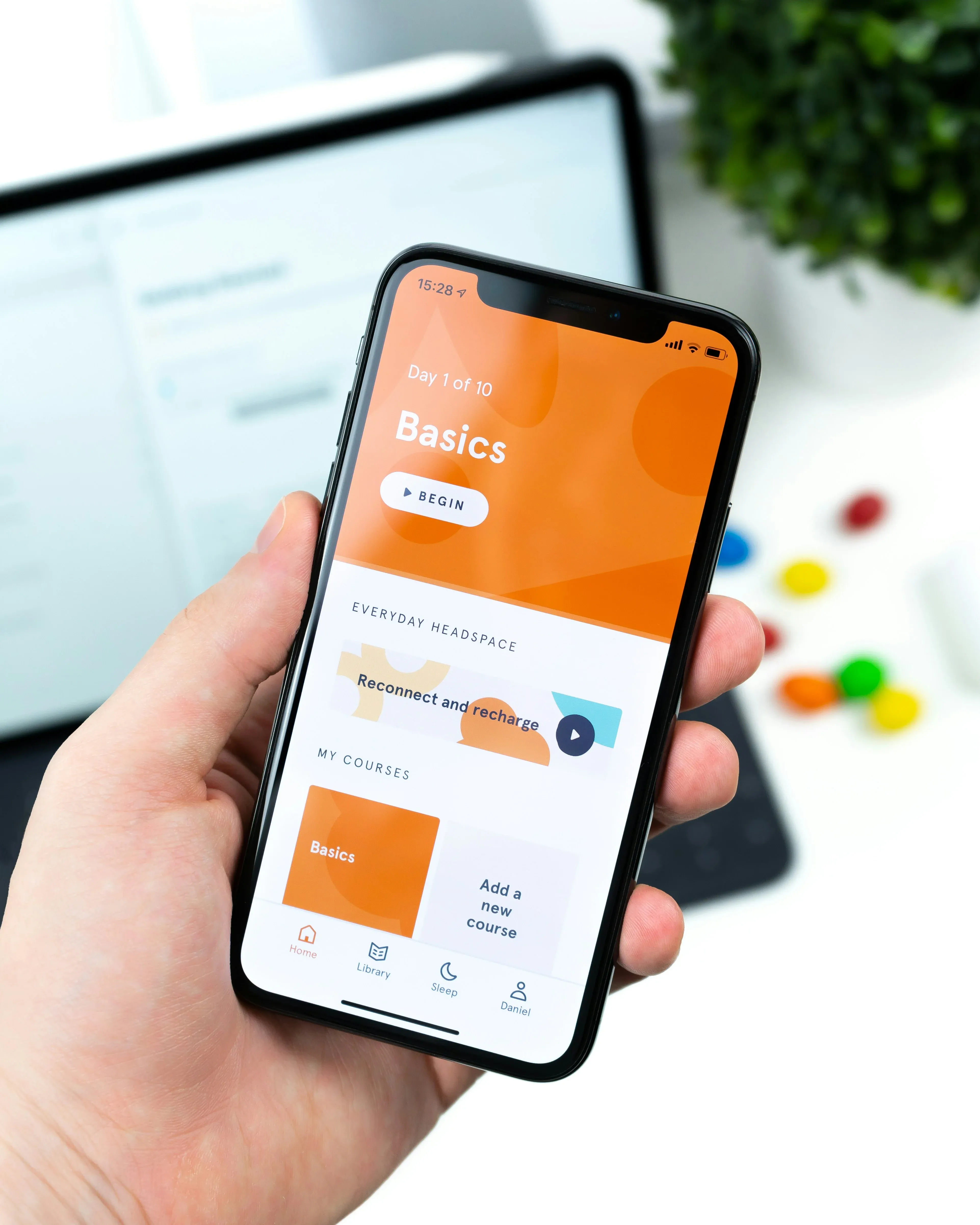A hand holding a phone showing a course-tracking app open on its home screen